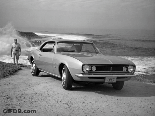 A 1967 Chevy Camaro Is Parked On A Dirt Road Near The Ocean GIF