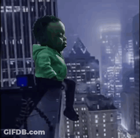 A Baby Dressed As The Hulk Is Sitting On A Person 'S Shoulders In Front Of A City Skyline . GIF