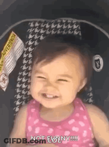 A Baby Girl Is Sitting In A Car Seat Smiling . GIF