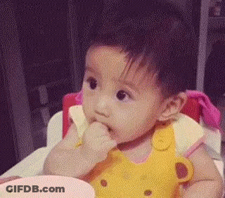 A Baby Girl Is Sitting In A High Chair Eating Food From A Bowl . GIF