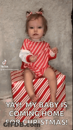 A Baby Girl Is Sitting On A Candy Cane Striped Box . GIF
