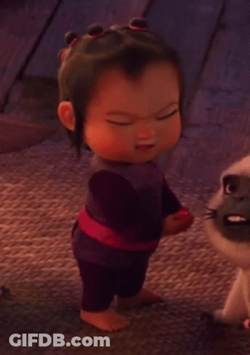 A Baby Girl Is Standing Next To A Cat And Making A Funny Face . GIF