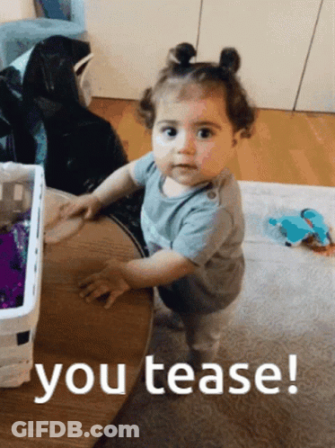 A Baby Girl Standing Next To A Table With The Words You Tease Written On The Bottom GIF