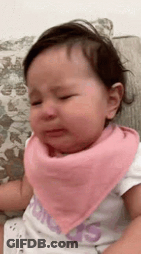 A Baby Girl Wearing A Pink Bandana Is Crying . GIF