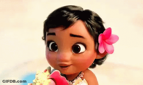A Baby Girl With A Flower In Her Hair Is Holding A Seashell . GIF