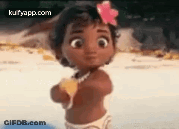 A Baby Girl With A Flower In Her Hair Is Standing On The Beach . GIF
