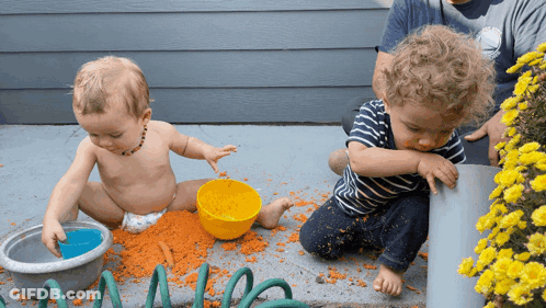 A Baby In A Diaper Is Playing With A Bowl Of Carrots GIF