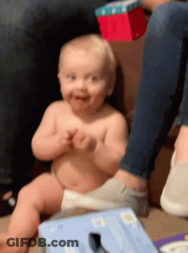 A Baby In A Diaper Is Sitting On The Floor Next To A Box That Says ' Socks ' On It GIF