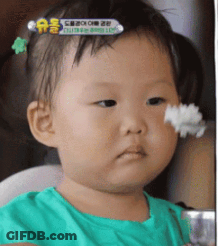 A Baby In A Green Shirt Is Eating Rice GIF