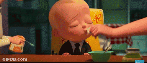 A Baby In A High Chair Is Being Fed With A Spoon . GIF