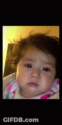 A Baby In A Pink And White Polka Dot Outfit Is Looking At The Camera GIF