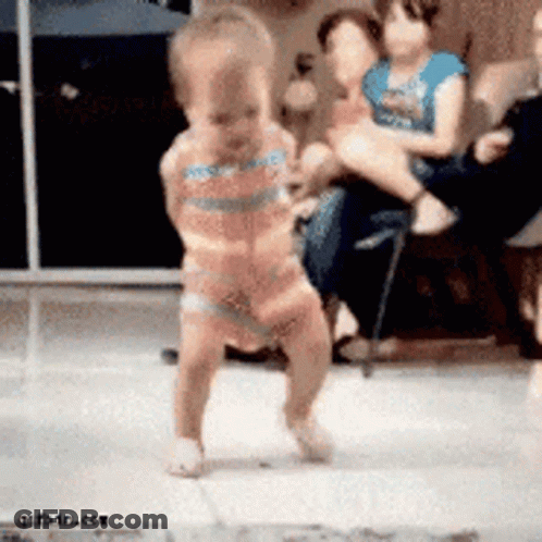 A Baby In A Pink Dress Is Dancing On A Tiled Floor GIF