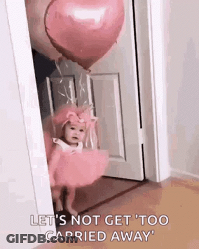 A Baby In A Pink Dress Is Standing In A Doorway With A Heart Shaped Balloon . GIF