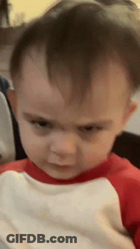 A Baby In A Red And White Shirt Looks Angry GIF