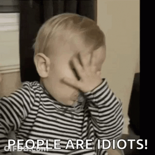 A Baby In A Striped Shirt Is Covering His Face With His Hand . GIF