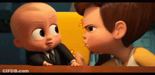 A Baby In A Suit And Tie Is Standing Next To A Boy In A Yellow Shirt And Talking To Him . GIF