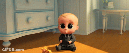 A Baby In A Suit And Tie Sits On The Floor Next To A Teddy Bear GIF