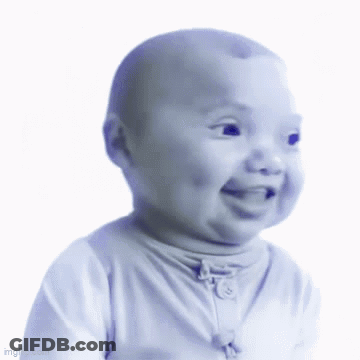 A Baby In A White Shirt Is Smiling And Looking At The Camera GIF