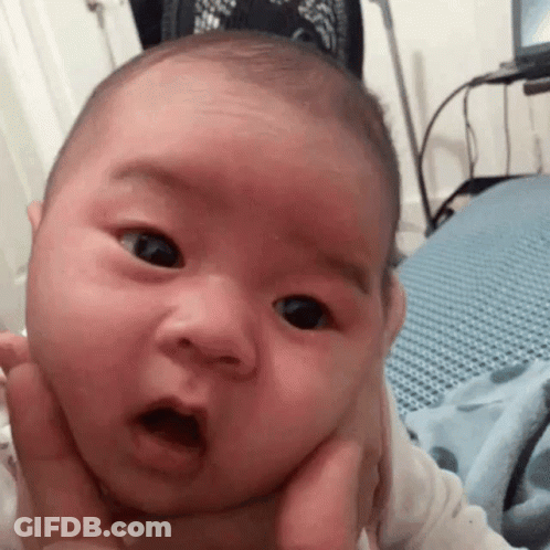 A Baby Is Being Held In Someone 'S Arms And Making A Surprised Face . GIF