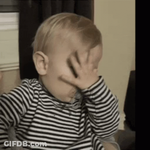 A Baby Is Covering His Face With His Hand . GIF