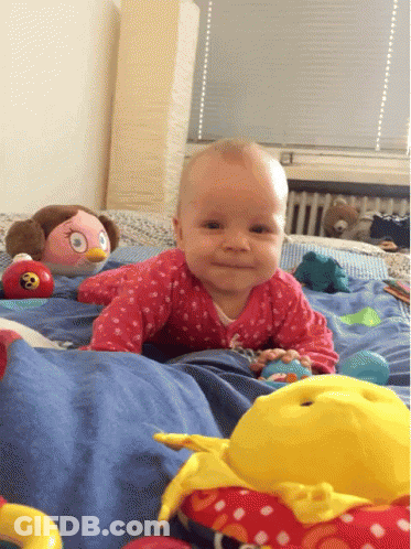 A Baby Is Crawling On A Bed With Toys GIF