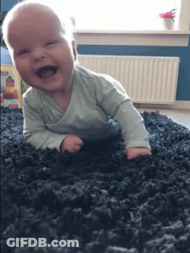 A Baby Is Crawling On A Carpet And Smiling GIF