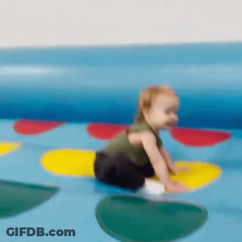 A Baby Is Crawling On A Colorful Twister Toy GIF