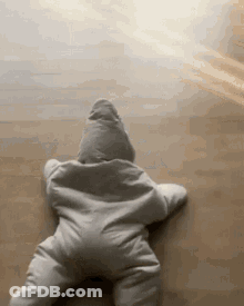 A Baby Is Crawling On The Floor In A Star Shaped Outfit . GIF