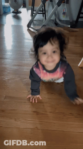 A Baby Is Crawling On The Floor Wearing A Shirt That Says ' Spiderman ' On It GIF
