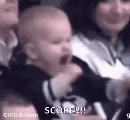 A Baby Is Crying In A Crowd While A Woman Holds Him . GIF