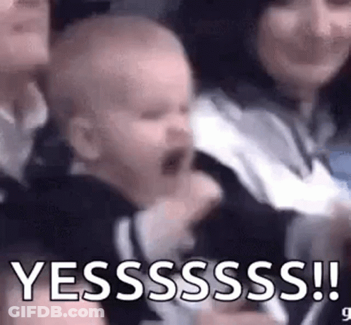 A Baby Is Crying In A Woman 'S Arms While Sitting In A Crowd Of People . GIF