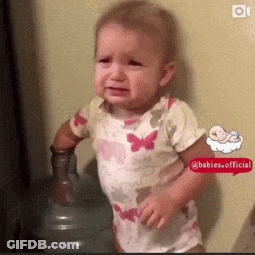 A Baby Is Crying In Front Of A Water Bottle . GIF