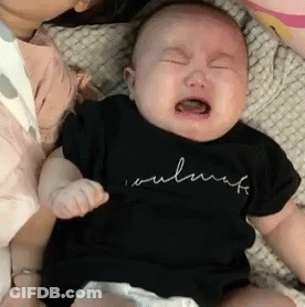 A Baby Is Crying While Being Held By A Woman And Wearing A Black Shirt . GIF