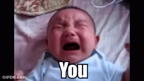 A Baby Is Crying While Laying On A Bed And The Baby Is Saying `` You '' . GIF