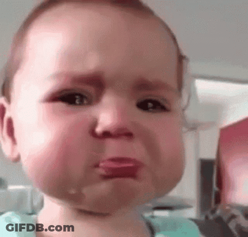 A Baby Is Crying With Tears Coming Out Of His Eyes And His Tongue Sticking Out . GIF