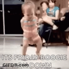 A Baby Is Dancing In Front Of A Group Of People . GIF
