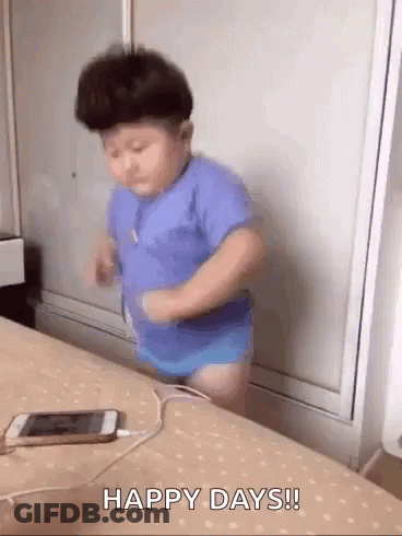 A Baby Is Dancing On A Bed Next To A Cell Phone And Headphones . GIF