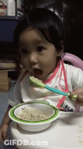 A Baby Is Eating From A Bowl With A Spoon In It GIF