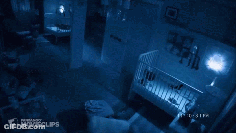 A Baby Is Laying In A Crib In A Dark Room With A Fandango Movieclips Logo In The Corner GIF