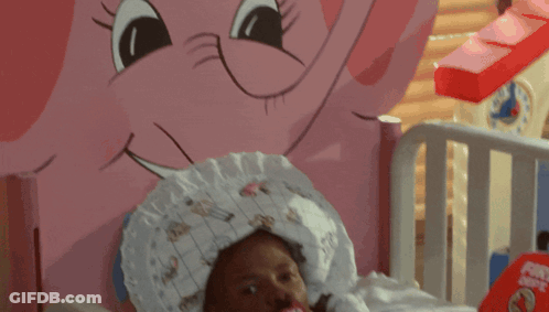 A Baby Is Laying In A Crib With A Pacifier In His Mouth And A Fire Helmet On The Bed GIF