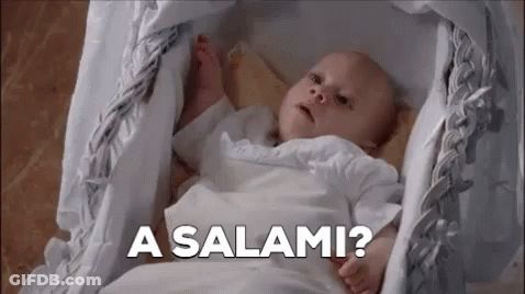 A Baby Is Laying In A Crib With The Words `` A Salami '' Written On The Bottom . GIF