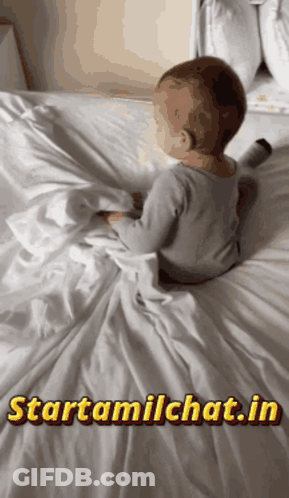 A Baby Is Laying On A Bed With The Website Starttamilchat.in Displayed GIF