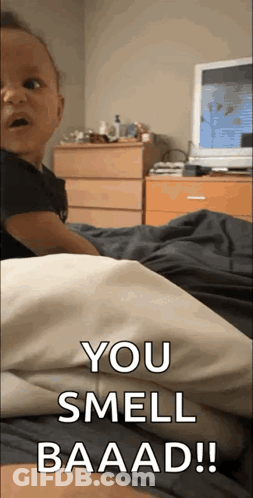 A Baby Is Laying On A Bed With The Words You Smell Baaad Written On The Bottom GIF