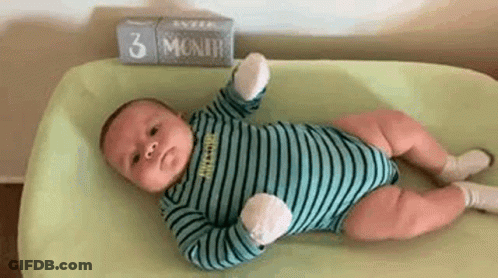 A Baby Is Laying On A Changing Table Next To A Sign That Says 3 Months . GIF