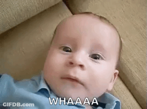A Baby Is Laying On A Couch And Making A Funny Face While Looking At The Camera . GIF