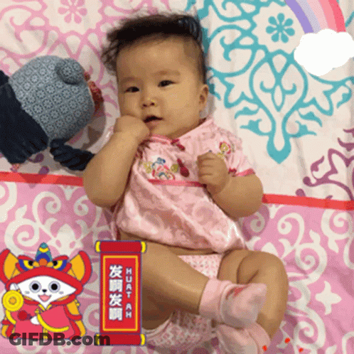 A Baby Is Laying On A Pink Blanket With A Sign That Says Huatah On It GIF