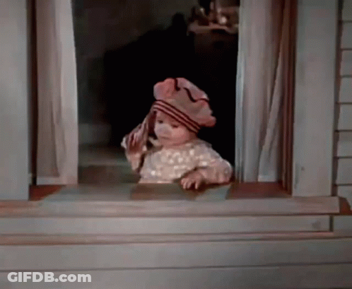 A Baby Is Looking Out Of A Window Wearing A Hat And Holding A Towel . GIF