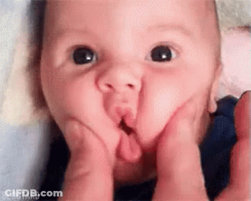 A Baby Is Making A Face With His Hands . GIF