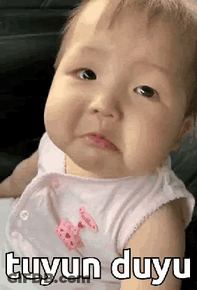 A Baby Is Making A Funny Face And The Baby Is Wearing A White Shirt . GIF