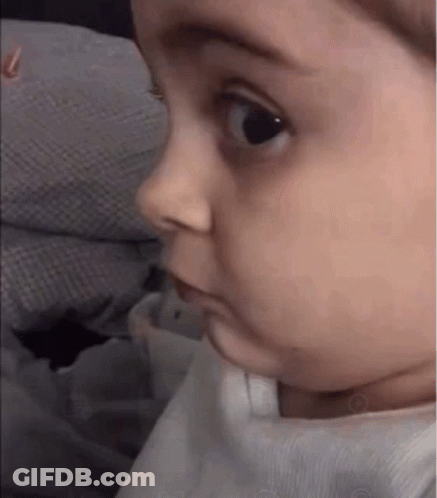 A Baby Is Making A Funny Face While Looking At The Camera . GIF